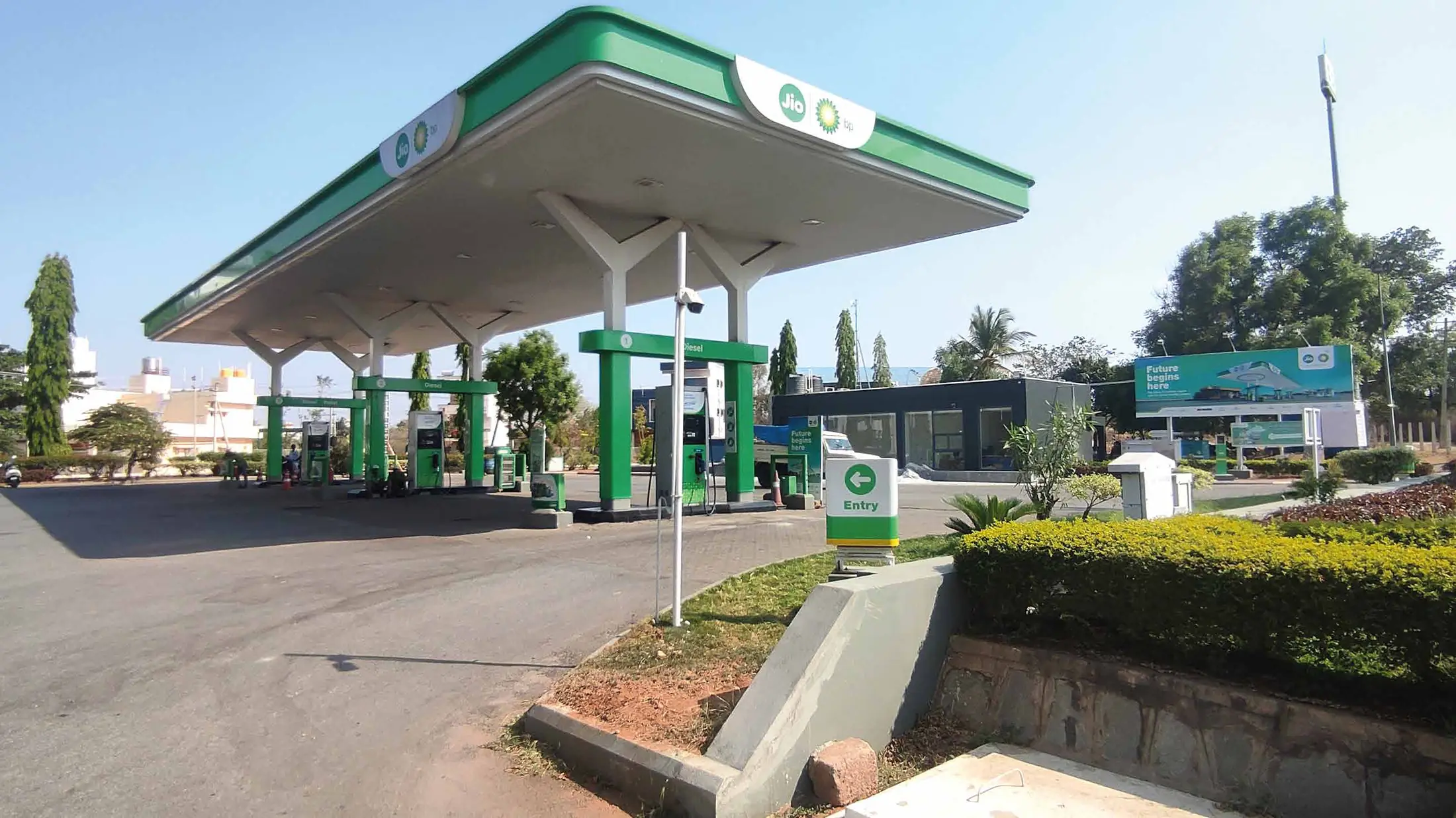 Jio-bp fuel station forecourt with green canopy fascia and entry signage